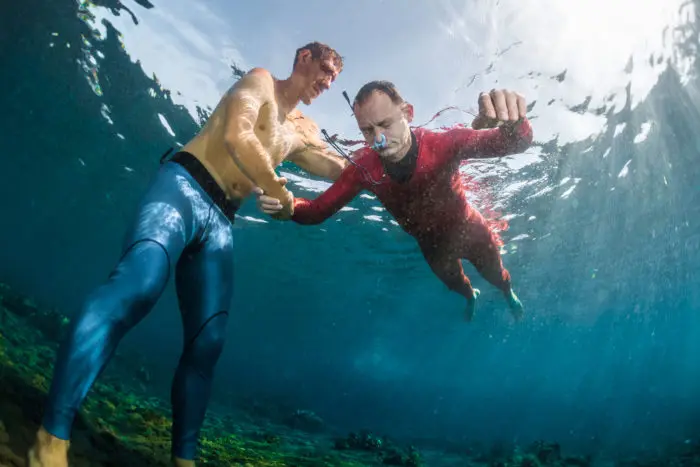 Freedivers training static breath-holding in the shallow water of a calm bay.