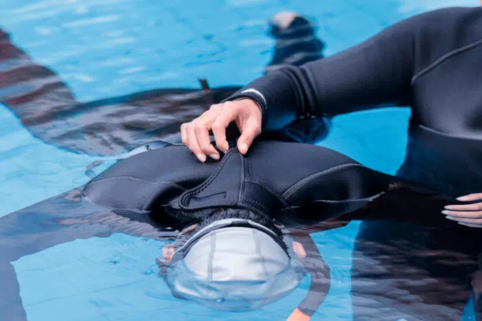 A freediving instructor buddying a student during a breath-hold.