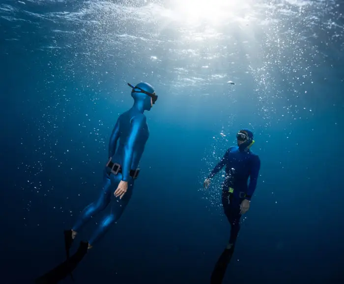 Two freediving buddies diving together.